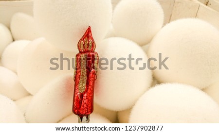Beautiful Christmas ornaments. Christmas decoration in the form of the red candle with gold glitter ornament, in the background, many whites Christmas balls.