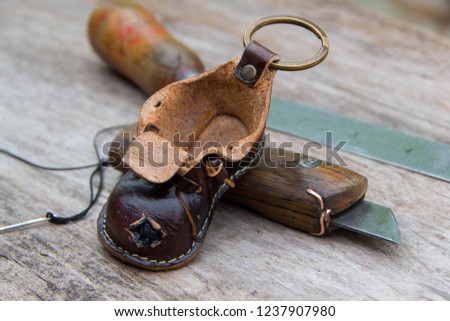 Colorfull leather key ring in the shape of old shoe on wooden background