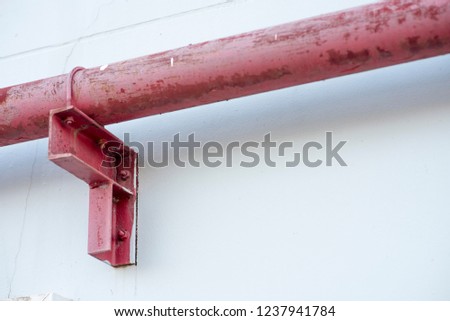 
A red fire hydrant is attached to the white wall