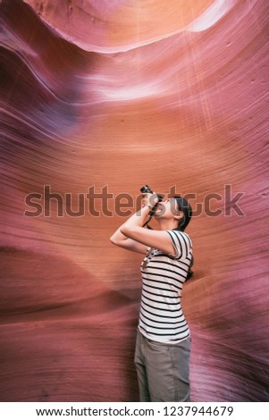 Nature Photographer taking pictures outdoors lower antelope canyon arizona. young lady lens man looking up by slr camera sunny sky. elegant asian hiker love traveling nature wild life concept.