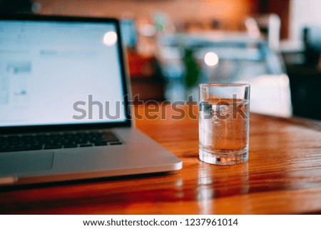 A cup of pure water with laptop on table. Royalty high quality free stock image of glass of water with laptop for working in a coffee shop. Beautiful workspace with retro and vintage style  
