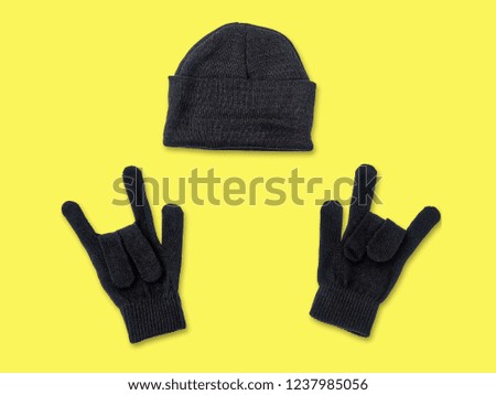 Black knitted hat beanie and gloves on a yellow background
