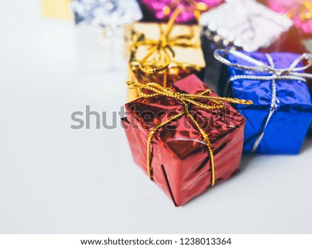 Close-up small colorful gift boxes on white background with copy space. Top view of many gifts wrapped colorful shiny paper.