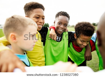 Junior football team huddling together Royalty-Free Stock Photo #1238027380