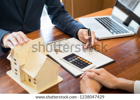Businessman signs contract behind home architectural model
Discussion with a real estate agent rental company staff 
at the office property appraisal and valuation concept