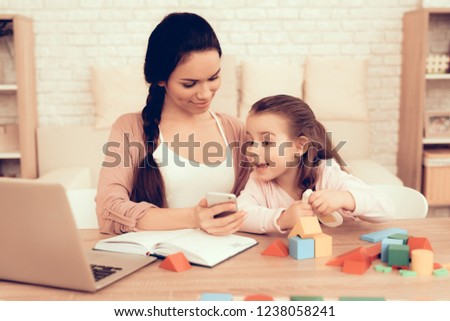 Mother with Phone Educational Games. Learning Child at Home. Child Development. Board Games for Children. Modern Learning for Children. Woman Working on Laptop. Happy Little Girl. Write on Notebook