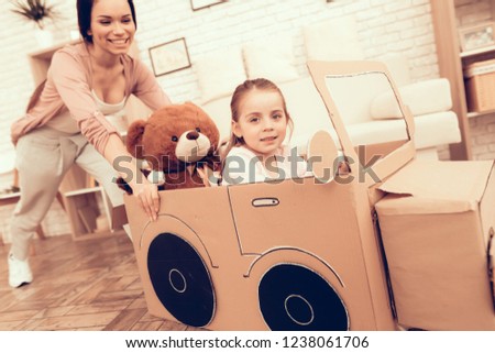 Rolls Girl in Cardboard Car. Child Development. Mom and Daughter Play. Happy Mom and Child Build Car. Woman and Daughter. Mother Teaches Daughter. White Interior. Car Made Cardboard. Handmade Toys.