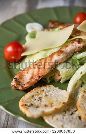 Fresh caesar salad in a green plate on a light wooden table pic