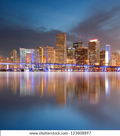 Miami Florida illuminated downtown buildings and bridge at sunset with reflections in the water of Biscayne Bay. Panoramic skyline of the World famous travel location.
