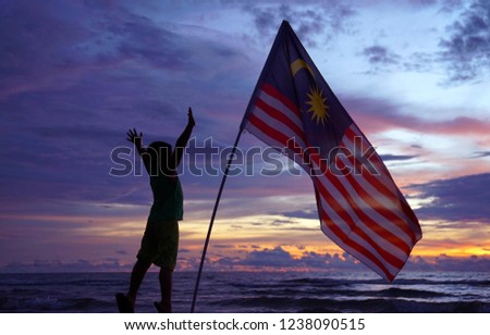Kids standing with Malaysia flag with sunset background. Independece Day concept. Concept image. 