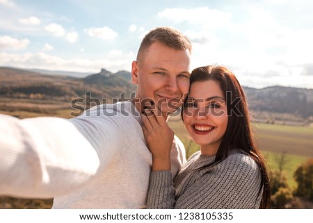 Happy young couple making selfie against the mountains. They smiling and hugging. Concept of travelling, freedom and love. Close up.