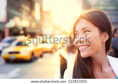 Asian woman Vivacious in New York City with a beautiful beaming smile backlit by the warm glow of the sun shining down a busy street with taxicabs in downtown Manhattan, New York City. Royalty-Free Stock Photo #123813202