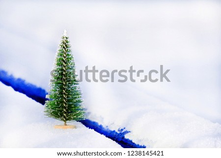 Artificial spruce on a blue snow-covered bench in the park. Attribute of the new year. Free space.