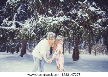 mother kissing her little daughter in the winter snowy forest