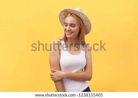 Young charming blond woman with happy exited emotional face looking at camera, isolated over yellow background