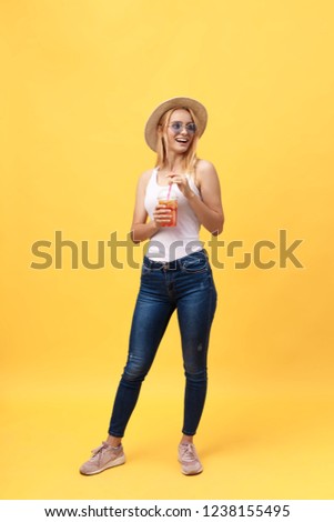 Full length portrait of a cheerful young woman wearing summer clothes while posing and looking at camera isolated over yellow summer background