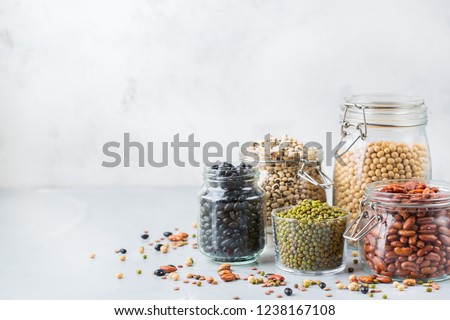 Healthy food, dieting, nutrition concept, vegan protein source. Assortment of colorful legumes in jars, lentils, soy kidney beans, chickpeas on a modern kitchen table. Copy space background Royalty-Free Stock Photo #1238167108