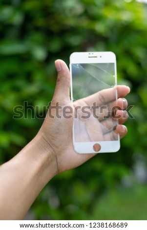 Close up hand hold smartphone, smartphone crack and green background