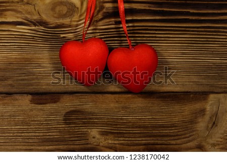 Two red hearts hanging over wooden background. Copy space
