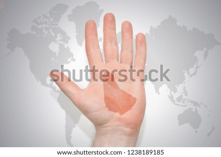 hand with map of barbados on the gray world map background. concept