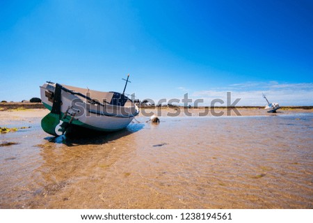 boat resting on sand at lowtide in summertime surround with clear water and boats in the background