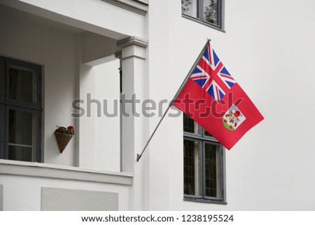 Bermuda flag hanging on a pole in front of the house. National flag waving on a home displaying on a pole on a front door of a building and raised at a full staff.