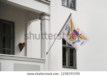 U.S. Virgin Islands flag hanging on a pole in front of the house. National flag waving on a home displaying on a pole on a front door of a building and raised at a full staff.