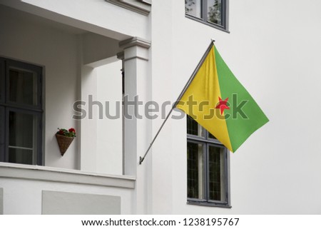 French Guiana flag hanging on a pole in front of the house. National flag waving on a home displaying on a pole on a front door of a building and raised at a full staff.