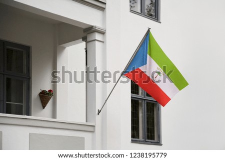Equatorial Guinea flag hanging on a pole in front of the house. National flag waving on a home displaying on a pole on a front door of a building and raised at a full staff.