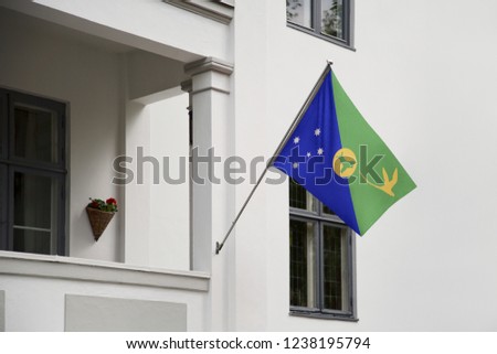 Christmas Island flag hanging on a pole in front of the house. National flag waving on a home displaying on a pole on a front door of a building and raised at a full staff.