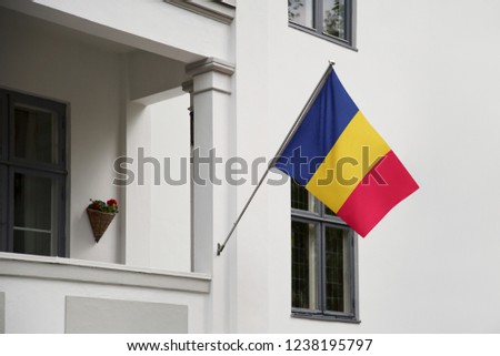 Chad flag hanging on a pole in front of the house. National flag waving on a home displaying on a pole on a front door of a building and raised at a full staff.
