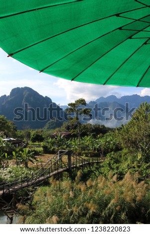 Wooden bridge over a river with the limestone mountains in the background in Vang Vieng, Laos 
