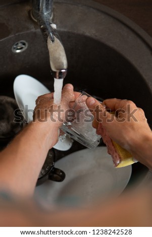 Picture from above of man's hands washing dish into sink