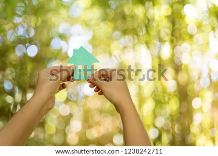 Paper house in hand outdoor.Human hand hold piece of house model 