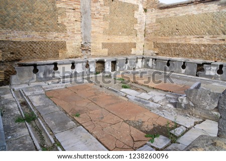 Ostia antica in Rome, Italy. Roman public latrine found in the excavations of Ostia Antica; unlike modern installations, the Romans saw no need to provide privacy for individual users. Royalty-Free Stock Photo #1238260096