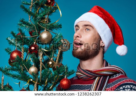 man in a festive hat standing near the Christmas tree                          