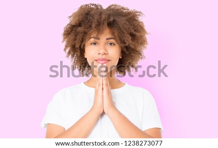 Praying young afro american girl. African woman in summer shirt isolated on pink background. Copy space. Mock up. Make a wish