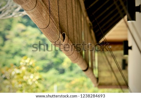 Bamboo blinds asian traditional home decoration. Sunlight coming through bamboo blinds by the window. Bamboo curtain at a window overlooking garden. Royalty-Free Stock Photo #1238284693