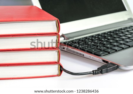 Pile of books connected to a computer via a USB cable