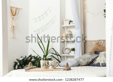 Modern Christmas interior of bedroom, Scandinavian style. White cozy bed with vintage pillow and Christmas lights