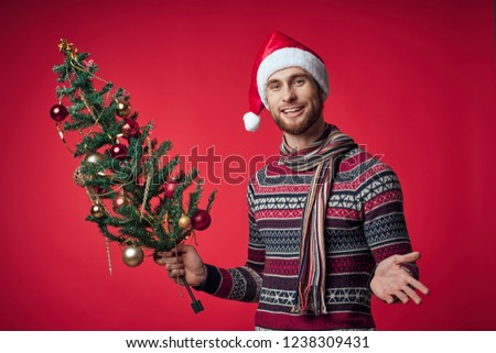 man with a Christmas tree in his hands on a red background                      