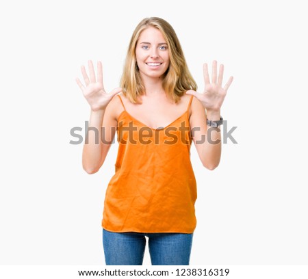 Beautiful young woman wearing orange shirt over isolated background showing and pointing up with fingers number ten while smiling confident and happy.
