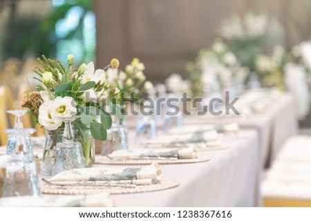 Setting of tables for Wedding celebration dinner with a white bouquet and beautiful flower.