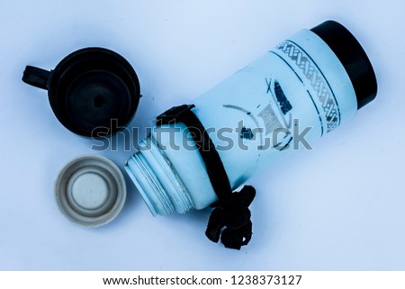 Close up of blue colored thermos isolated on white with a black colored cup with it.