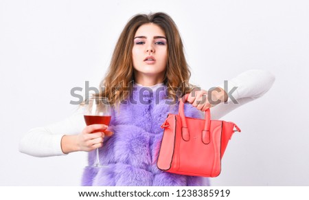 Girl wear fashion fur vest while posing with bag. Luxury store concept. Elite fashion clothes. Lady likes shopping. Designer clothing luxury fashion boutique. Woman with handbag hold glass of wine.