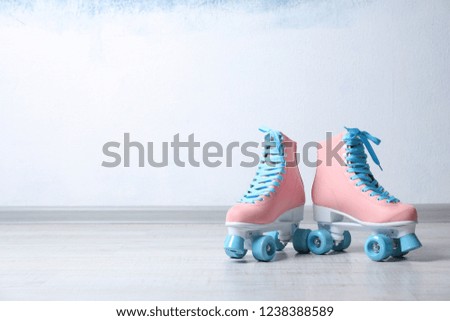 Vintage roller skates on floor near color wall. Space for text
