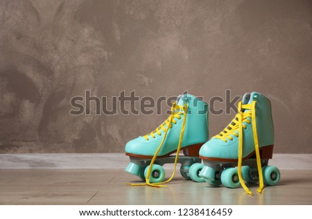 Vintage roller skates on floor near brown wall. Space for text