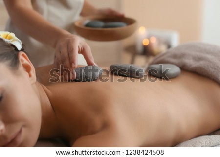 Beautiful young woman getting hot stone massage in spa salon Royalty-Free Stock Photo #1238424508