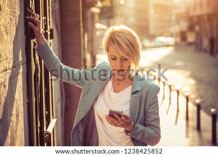 Stylish mid-age woman texting on the street
