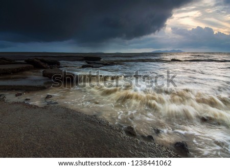 Cloudy sunrise over rocky pebbles foreground with water flow at Mersing, Johor, Malaysia
